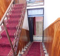 A hallway in a family house with a red carpet and walls with wooden decor.