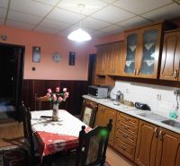 A kitchen with wooden decor, a dining table, and cabinets in a family house.