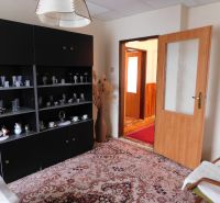 Living room of a family house with a dark cabinet, decorative glasses, and open doors.
