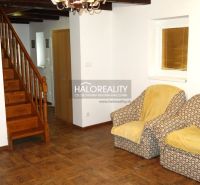 A room in a family house with a staircase, chairs, and a floor with a wooden decor.