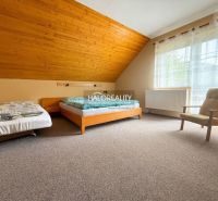 A room with two beds, an armchair, and a floor with a wooden decor in hotels and guesthouses.
