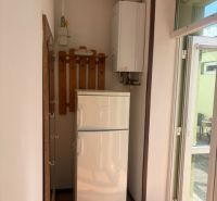 Kitchen in a studio apartment with a refrigerator, gas boiler, and coat rack.