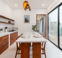 Dining room in a villa with wooden decor, set table and large window to the terrace.