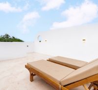 Sun loungers on the terrace of a villa in Bali under a blue sky.
