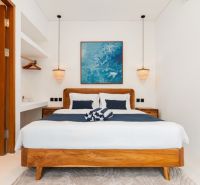 Bedroom with a wooden bed, pendant lamps, and a blue painting in a villa room.