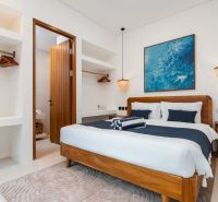 Bright bedroom in a villa with wooden furniture and a painting above the bed.