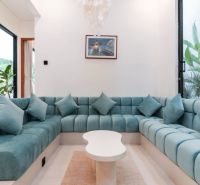 A comfortable blue couch in the interior of a villa with windows and plants.