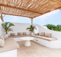 A villa with a terrace and white seating surrounded by green plants in Bali.