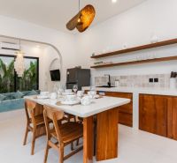 The kitchen in the villa with a dining table, wooden furniture, and a view of the garden.
