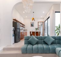 Living room in a villa with a turquoise sofa, dining table, and wooden decor.