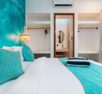 A bedroom in a villa with turquoise details and an entrance to the bathroom.