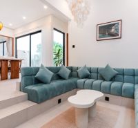 Living room in a villa with a turquoise sofa and a wooden dining table.