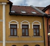 A building in Topoľčany with a historical facade and parked cars in front of it.