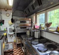 A kitchen in commercial premises with appliances and stainless steel counters.