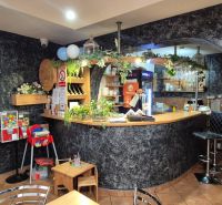 Interior of commercial premises with a bar counter, flowers, and a children's corner.
