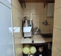 A narrow kitchenette in commercial premises with vegetables and a stainless steel sink.
