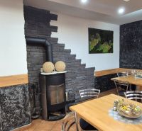 Commercial space with a wood-burning stove, wooden tables, and floral decorations on the walls.