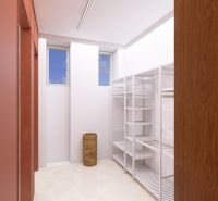 A wardrobe in a 3-room apartment with white shelves and windows letting in light.
