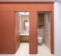 A bathroom with orange doors, a sink, and a mirror in a three-room apartment.