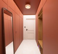 A narrow hallway in a 3-room apartment with orange walls and a mirror.