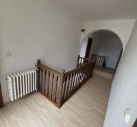 A hallway in a family house with a wooden decor floor and wooden railing.