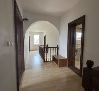 Hallway in a family house with a wood-patterned floor and wooden railing.