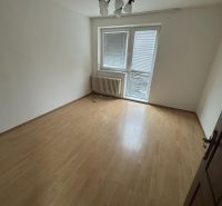 An empty room with a wood-patterned floor and a radiator in a family house.