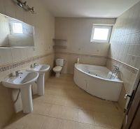 A bathroom in a family house with two sinks and a corner bathtub.