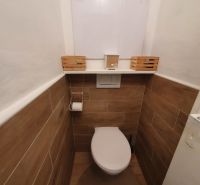 A toilet with wood-effect tiles in a 3-room apartment.