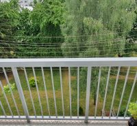 A balcony in a 3-room apartment on Nábrežná Street in Trenčín with a view of greenery.