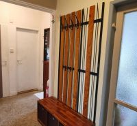 A hallway of a 3-room apartment with a coat rack and practical storage space.