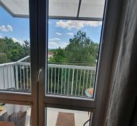 View from a 3-room apartment to a balcony overlooking greenery and clouds.