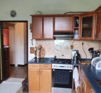 A kitchen in a 3-room apartment with a gas stove, wooden cabinets, and a floor with a decor.