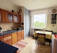 A kitchen in a 3-room apartment with a wooden decor floor and light furniture.