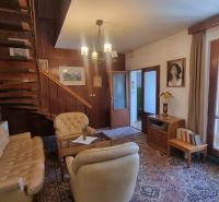 Interior of a family house with a cozy living room, wooden staircase, and light furniture.