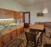 A kitchen in a family house with wooden cabinets, a corner sofa, and a dining table.
