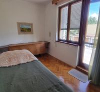 A bedroom in a family house with wooden decor and a large window.