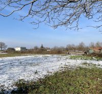 Snow-covered residential plots in the village of Vrakúň, street not specified, with visible houses in the background.