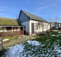 A family house in Vrakúňa with a lawn, remnants of snow, and an adjacent wooden structure.