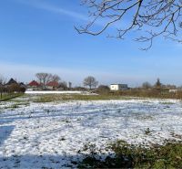 Snow-covered land in Vrakúňa with trees and houses in the background. Plots - residential.