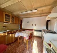 A kitchen with wooden cabinets and a dining table in the plots - living.