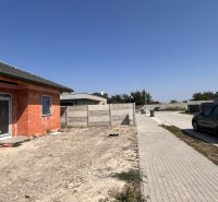 An unfinished family house in Povoda near an unspecified street, next to a paved road and a car.