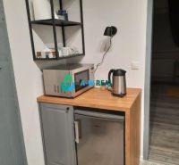 Kitchen corner in a family house with a microwave, refrigerator, and wooden decor flooring.