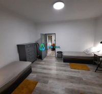 A room in a family house with two beds, gray furniture, and a wooden decor floor.