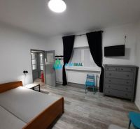Bedroom in a family house with a wooden decor floor, bed, and dresser.