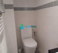 A bathroom in a family house with white tiles and patterned flooring.