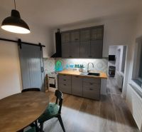 A kitchen with a wooden decor floor in a family house, with gray cabinets and a table.