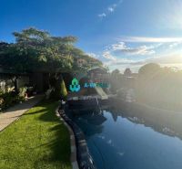 The garden of a family house in Orechová Potôň with a swimming pool and greenery under the blue sky.