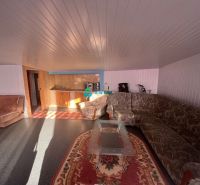 Living room with a sofa and a kitchenette in a family house with a wooden decor floor.
