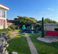 The garden of a family house in Orechová Potôň with a swimming pool, lawns, and a statue.